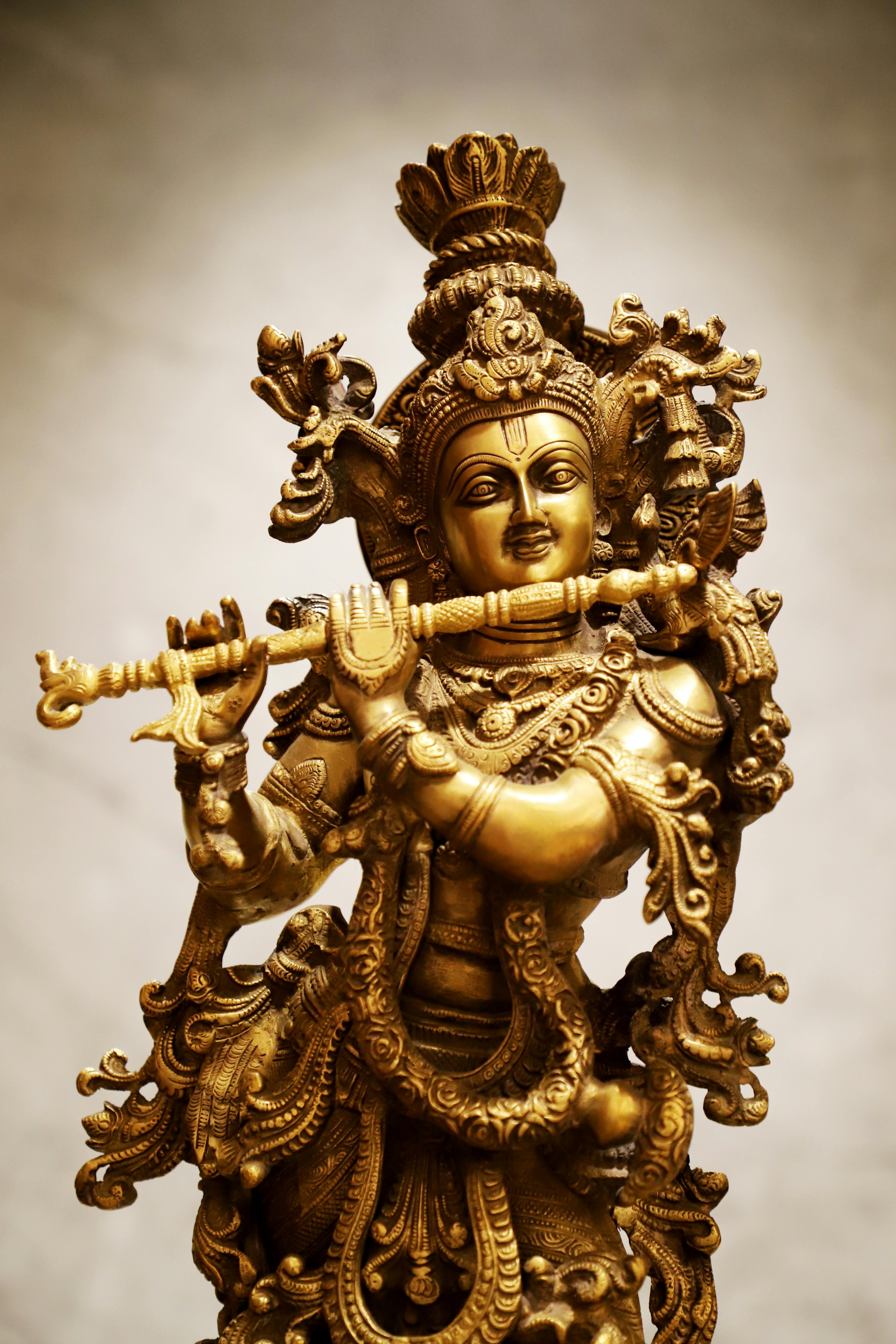 Intricate brass sculpture of a Hindu deity holding a flute, symbolizing divine music and spirituality.