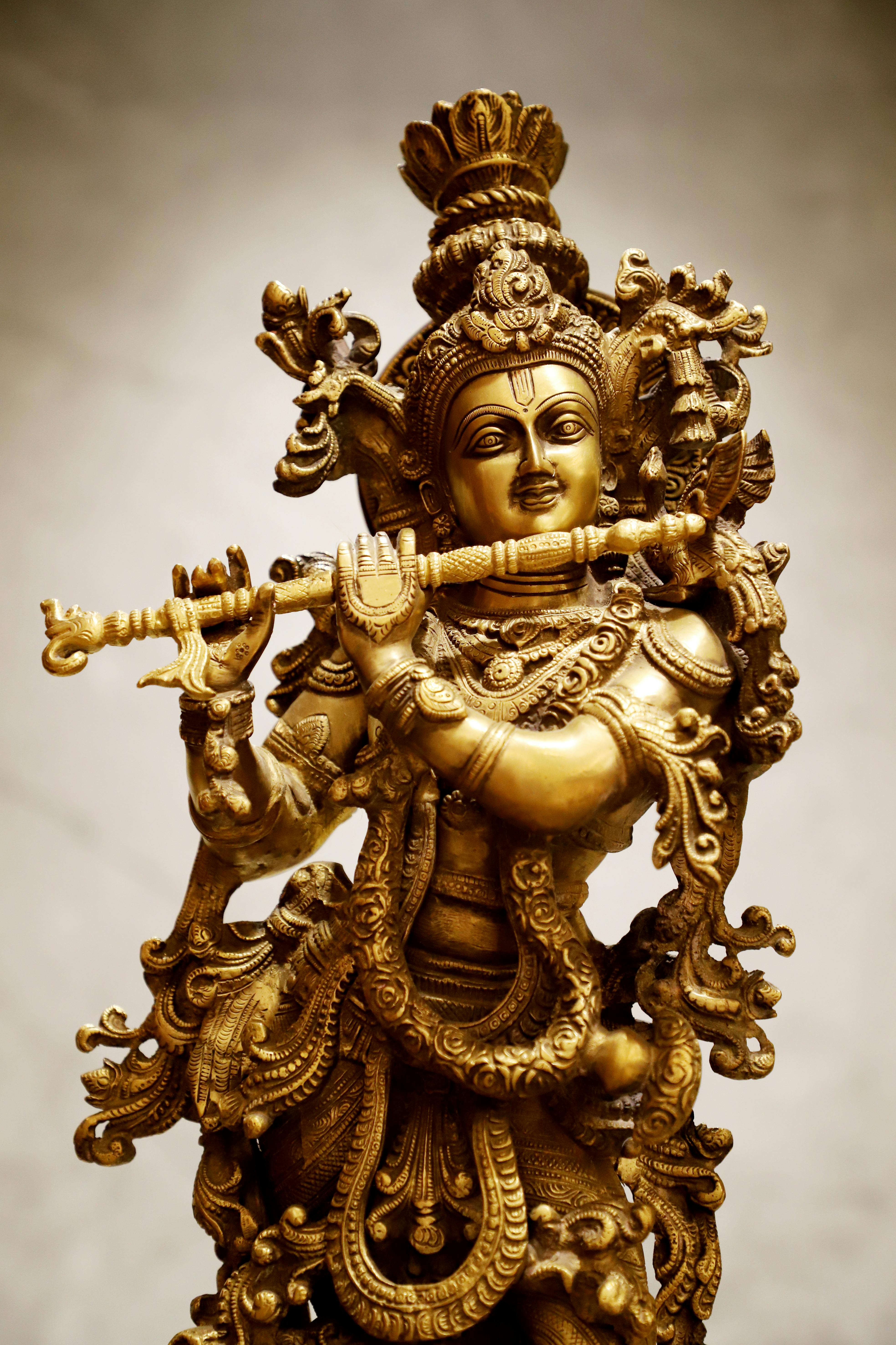 Exquisite golden statue depicting a Hindu deity playing a flute, showcasing intricate craftsmanship.