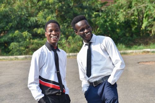 Free Two young men share a cheerful moment outdoors in Ife, Osun, Nigeria, dressed in formal attire. Stock Photo
