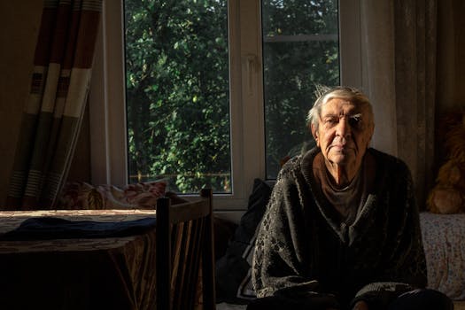 一位老人独自坐在舒适的房间里，阳光透过窗户照射进来