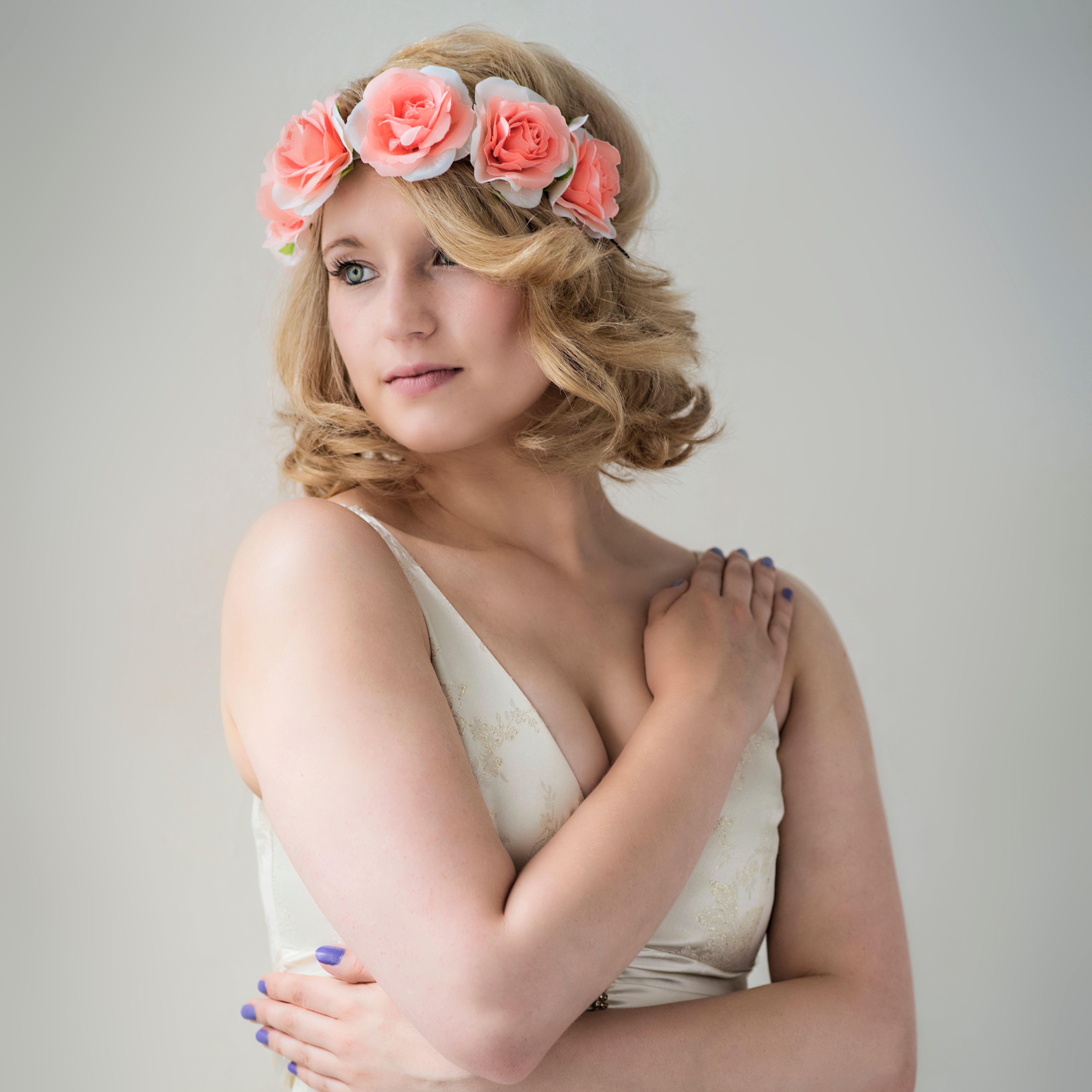 A graceful woman in a floral headband poses intimately against a neutral background.