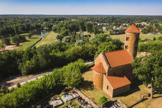 Aerial shot of a historic church surrounded by greenery in a serene countryside landscape.