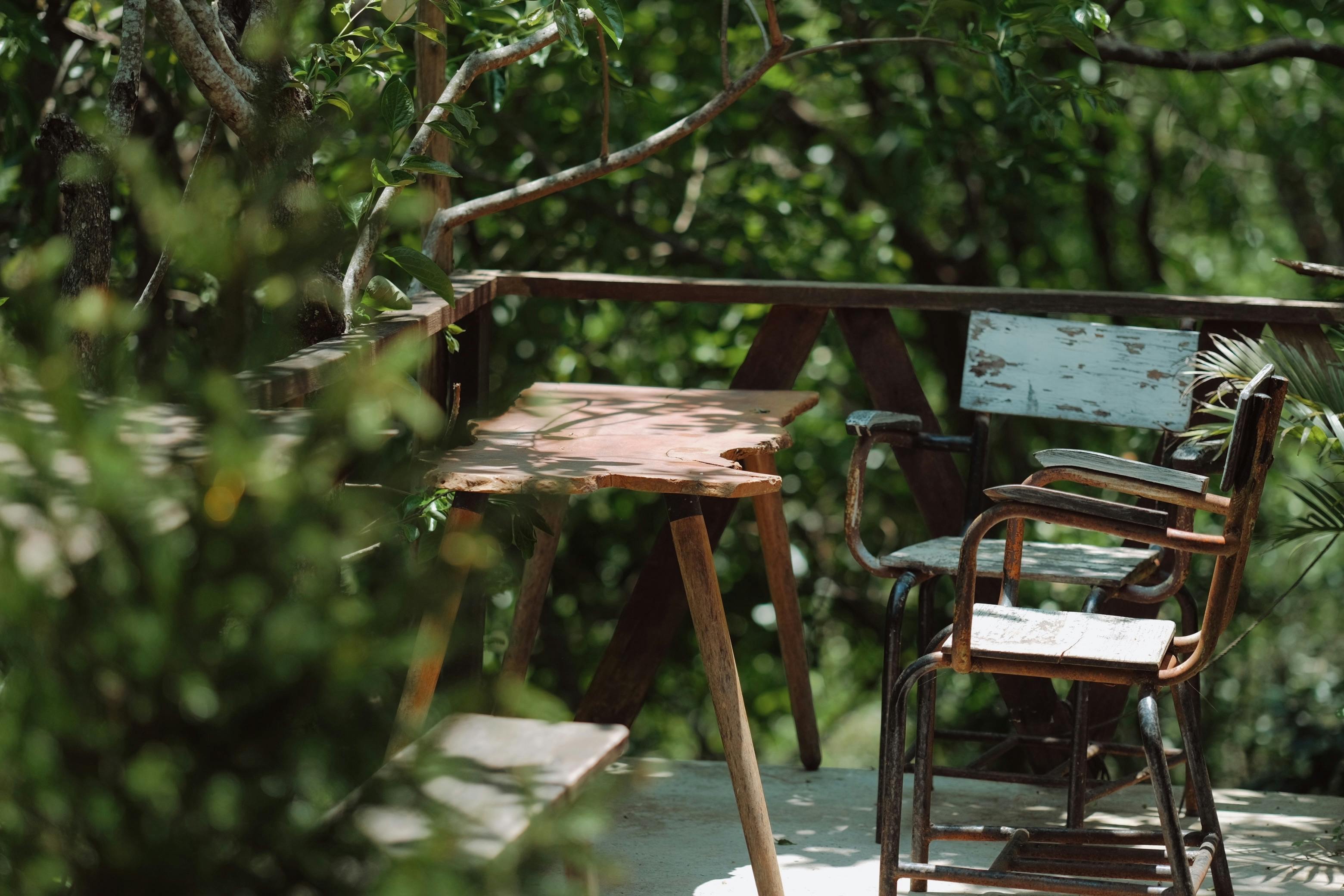 Peaceful outdoor deck with wooden chairs surrounded by lush greenery, perfect for relaxation.