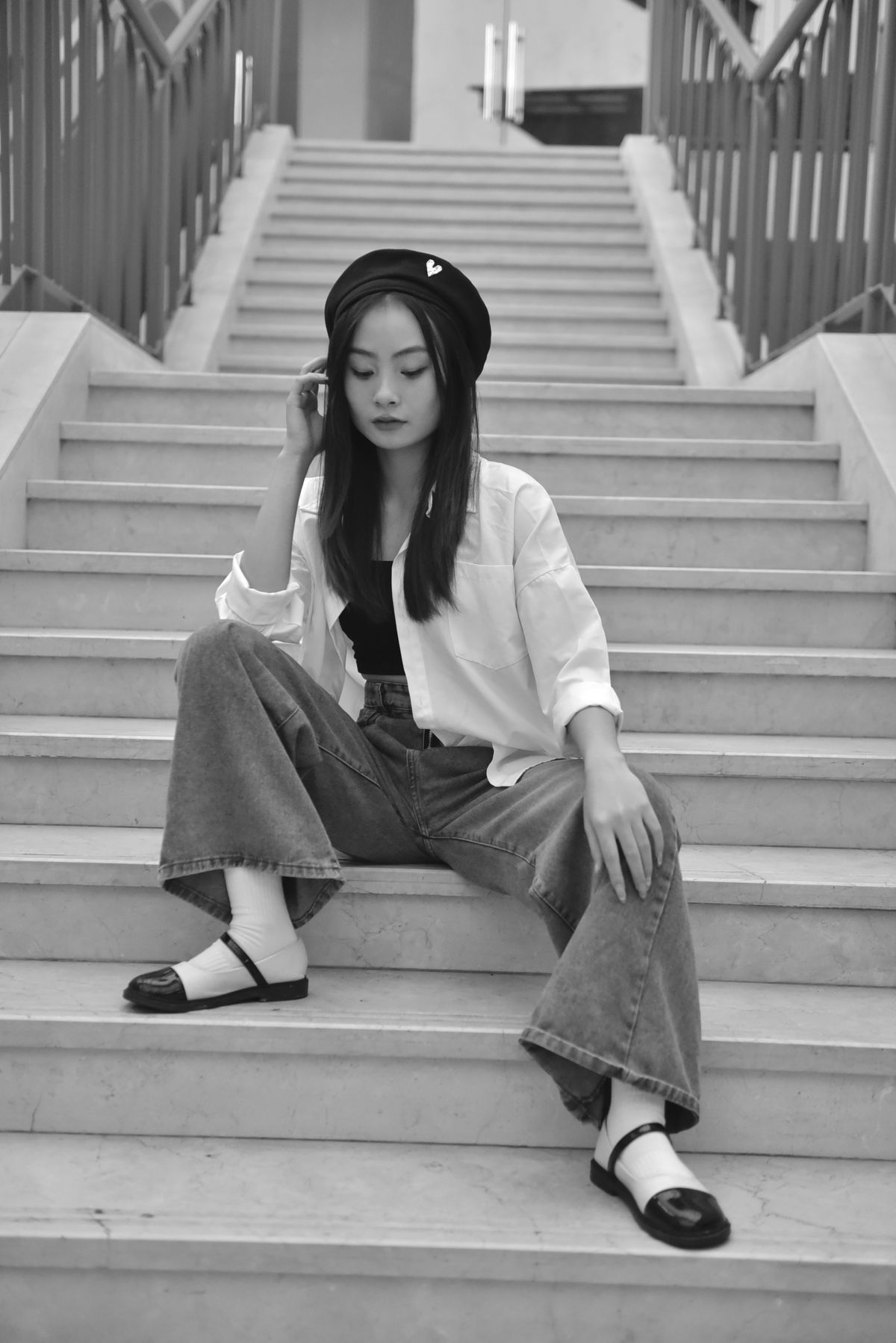 A stylish young woman sitting on marble stairs in flats — the flat as leveller