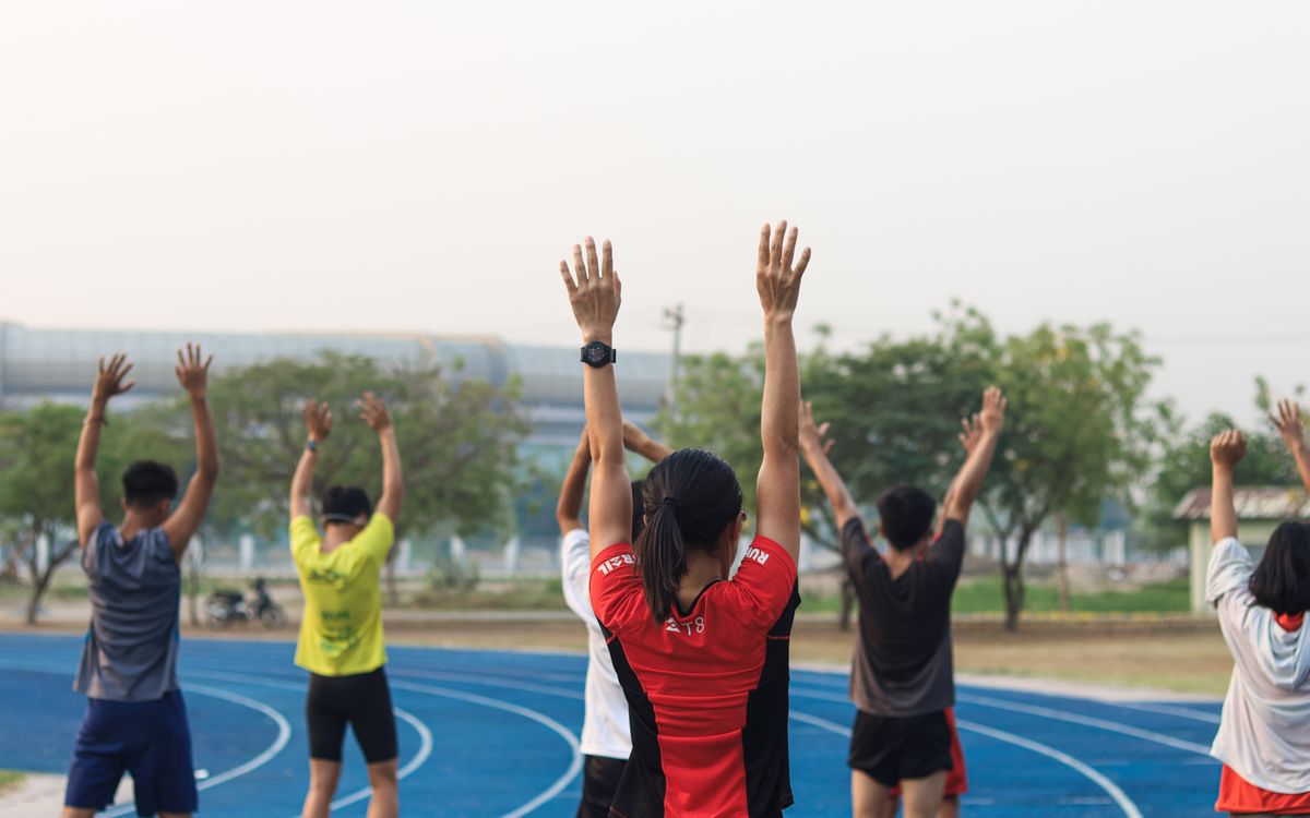 A group of adults exercising on a blue running track in Mandalay, Myanmar.