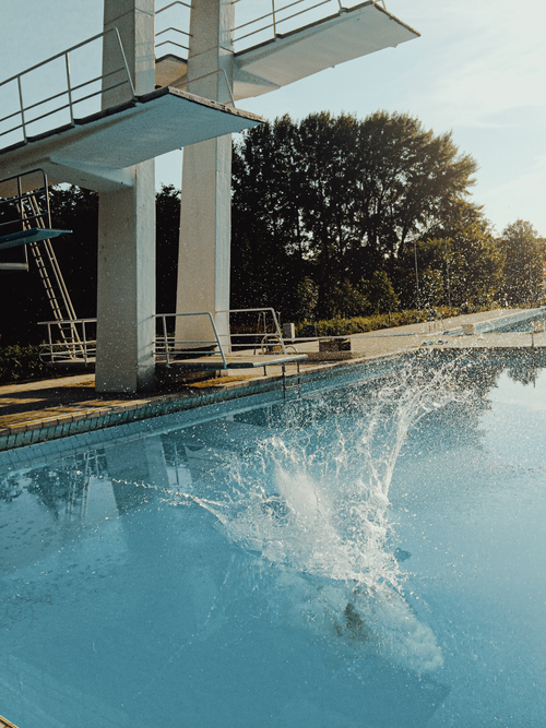 Free A high dive splash at an outdoor swimming pool under sunny skies. Stock Photo