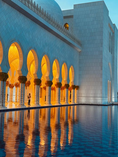 Free Serene view of Sheikh Zayed Grand Mosque with glowing arches reflecting in water at twilight. Stock Photo