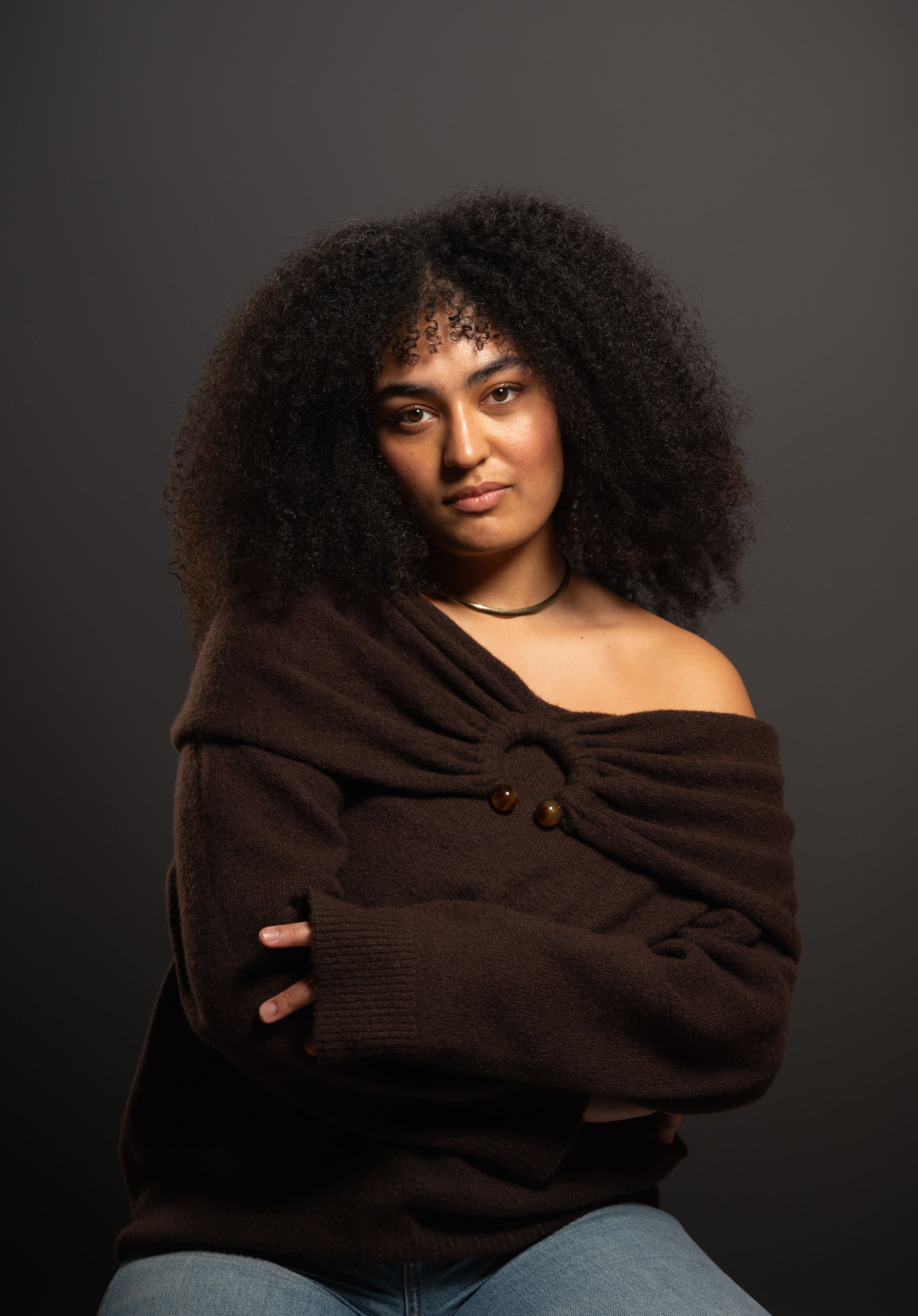Portrait of a confident young woman with curly hair in studio lighting.