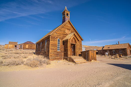 Explore the rustic charm of Bodie's historic wooden church under a bright blue sky.