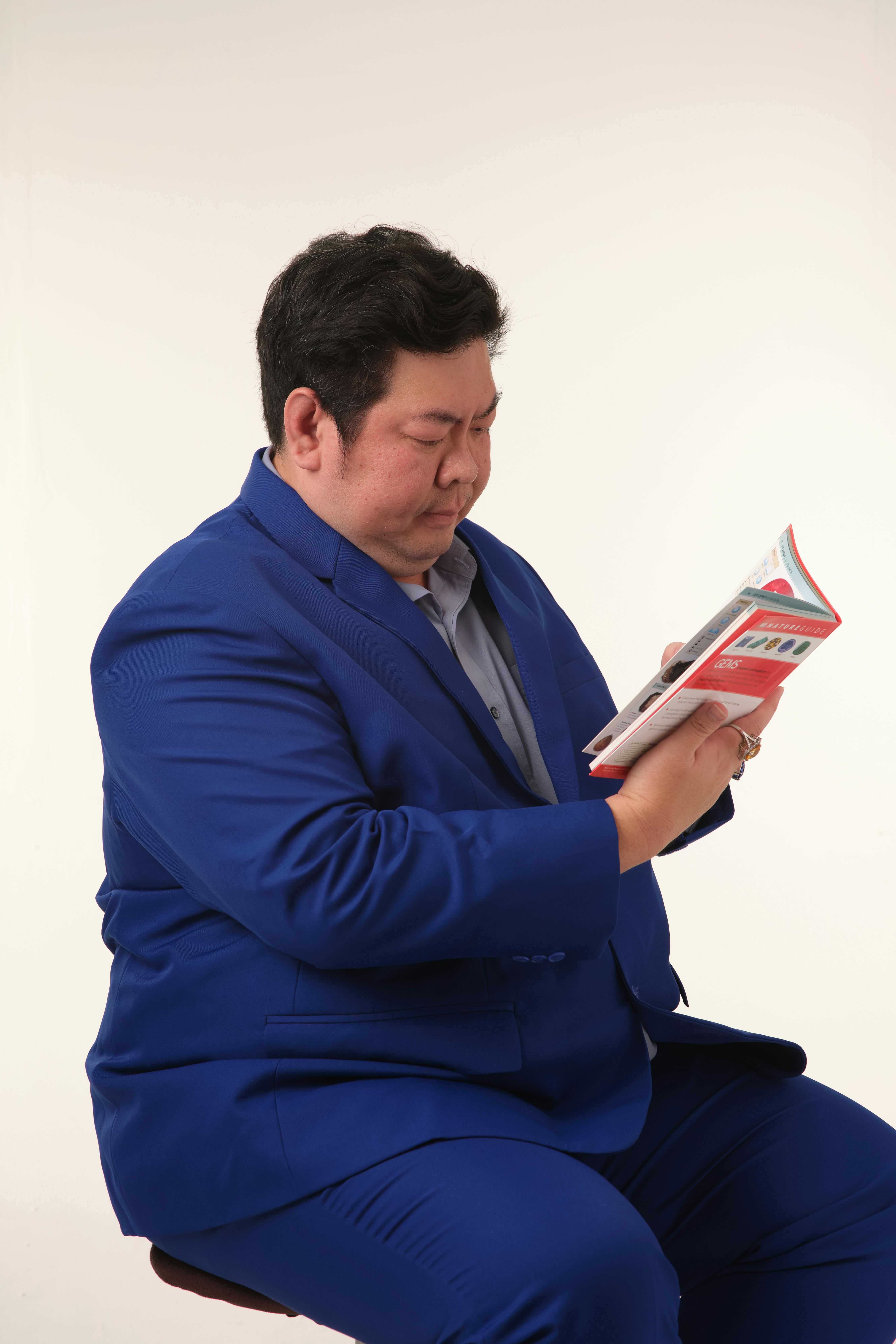 bezplatná Dospělý muž v modrém obleku čte časopis v prostředí studia. Základová fotografie