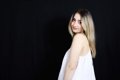 Free Elegant portrait of a young woman in a white dress against a dark background. Stock Photo