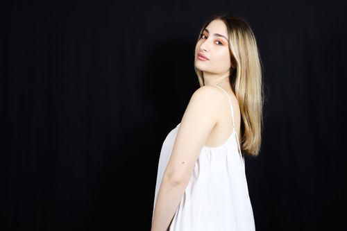 Free Elegant portrait of a woman in a white dress with a black backdrop, showcasing natural beauty and fashion. Stock Photo
