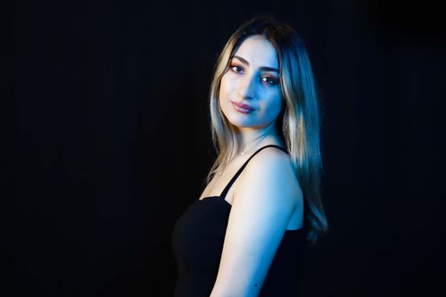 Free Stylish portrait of a woman in black dress with blue lighting against dark background. Stock Photo