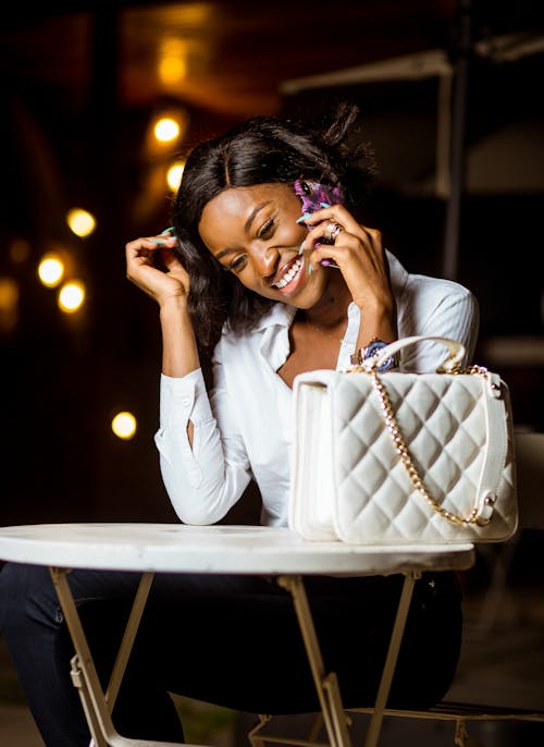 Free Woman in White Top and Black Pants Sitting Holding a cellphone  Stock Photo