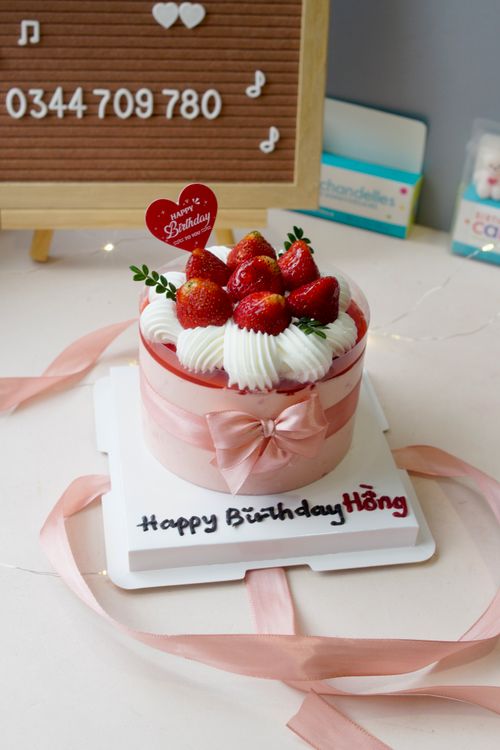 Free A stylish strawberry birthday cake with whipped cream and pink ribbon decor. Stock Photo