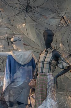 Stylish mannequins in a Manhattan store window featuring plaid fashion and transparent umbrellas.