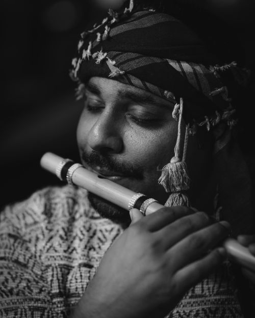 Free Artistic black and white portrait of a musician playing the flute, showcasing traditional attire and cultural expression. Stock Photo