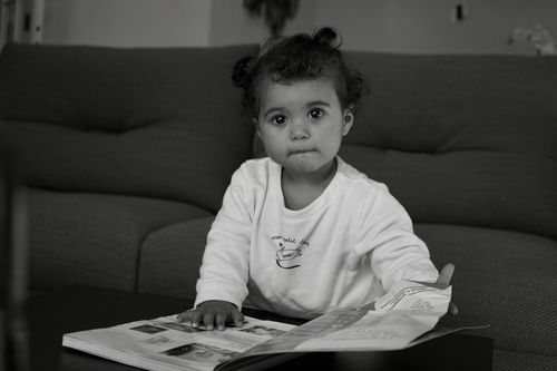 Free Black and white photo of an adorable toddler engaged with a book indoors. Stock Photo