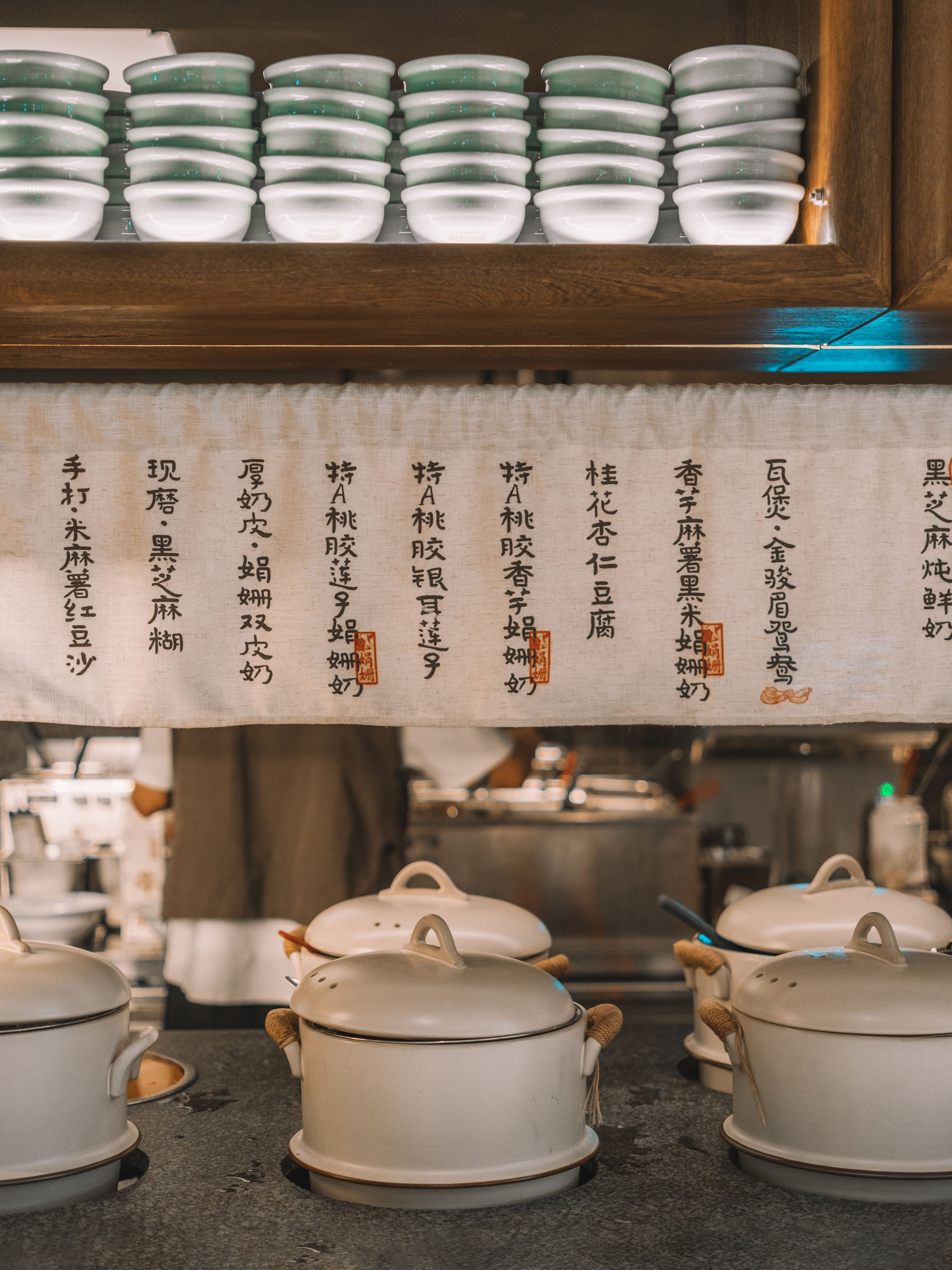 Warm and inviting restaurant kitchen with Asian-style decor and traditional cookware on display.