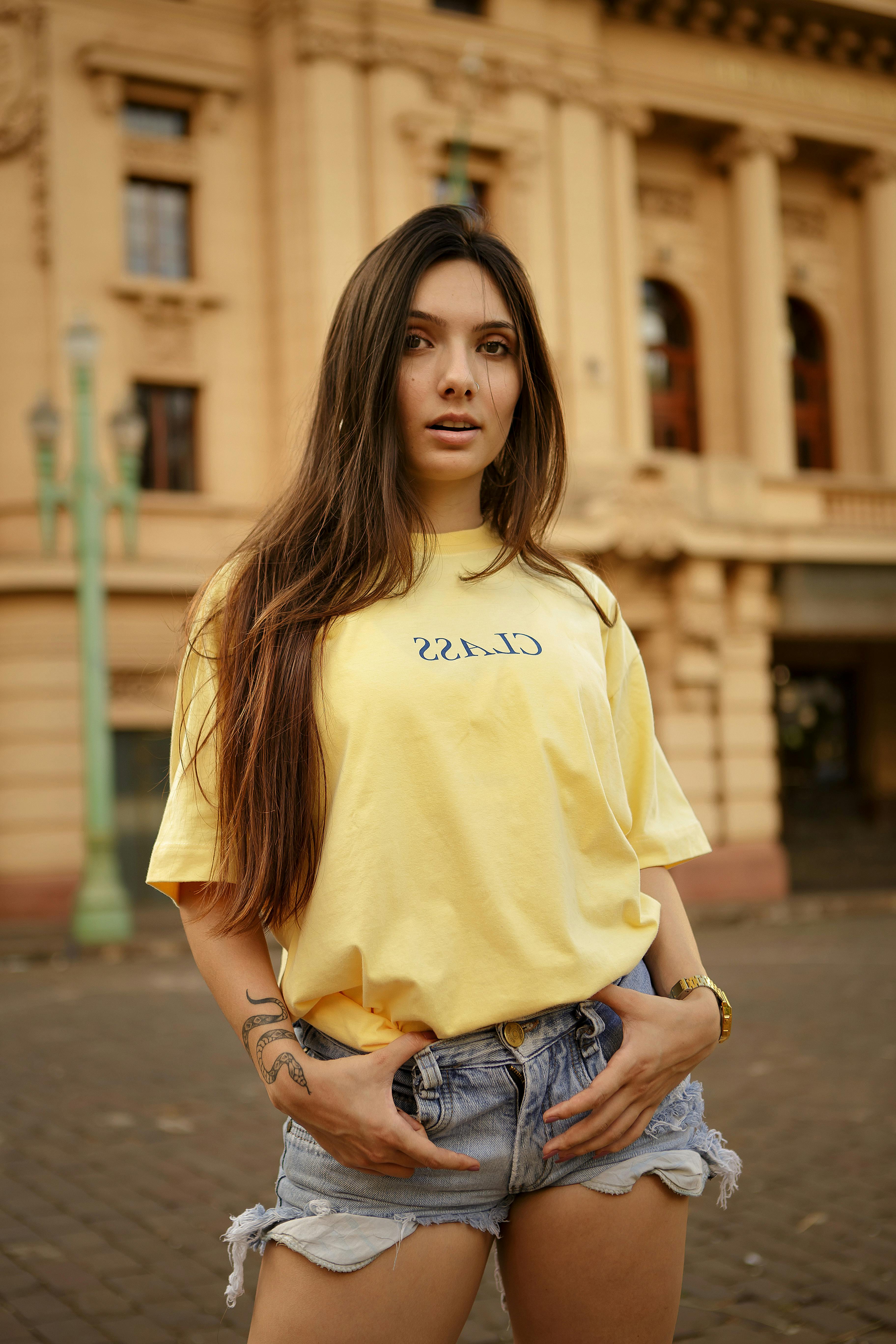 一位穿着黄衬衫的纹身女子在经典建筑前摆姿势