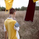 一个留着短发、戴着大耳环的女人正在田野里晾衣服