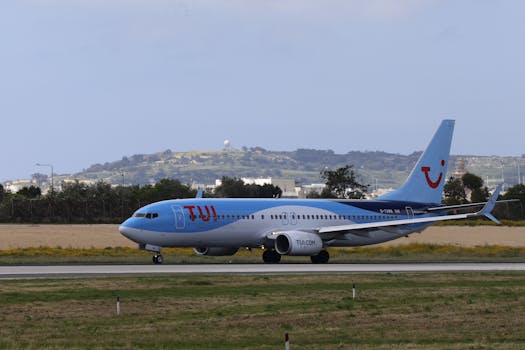 TUI aircraft preparing for takeoff on a sunny day with landscaped hills in the background.