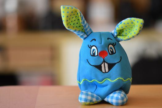 Cute blue plush Easter bunny toy with checkered feet and polka dot ears for children's fun.