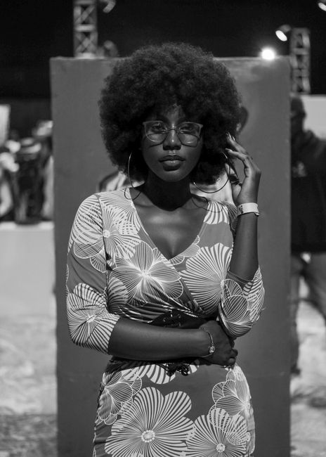 Elegant woman with afro hairstyle in a floral dress at nighttime outdoor event.