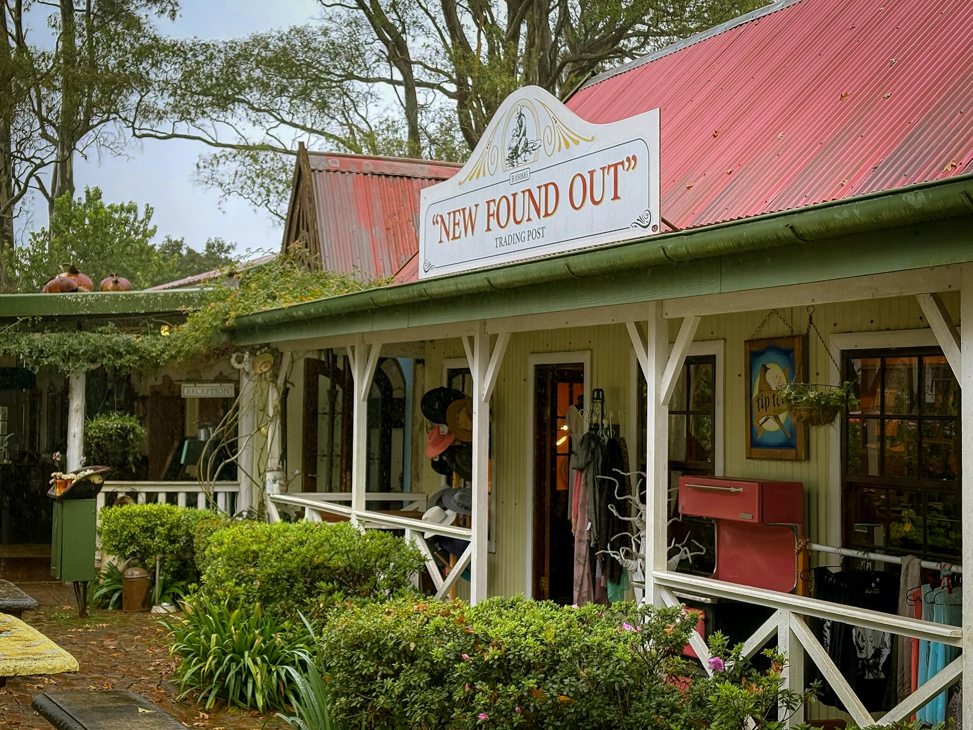 Charming vintage trading post with red roof and lush greenery, perfect for a quaint village visit.