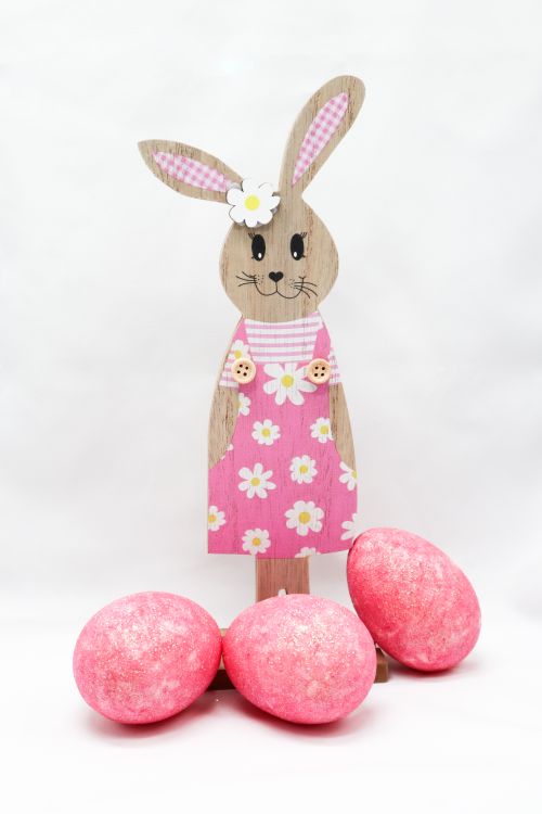 Free Adorable wooden bunny with pink eggs for Easter decoration. Perfect for festive home styling. Stock Photo