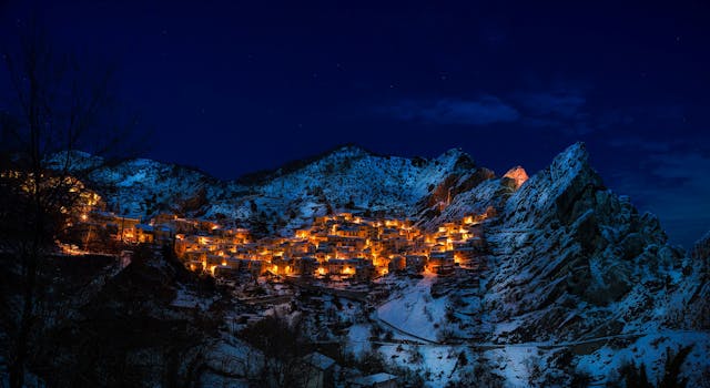 A captivating winter scene of a snow-covered mountain village illuminated at night.
