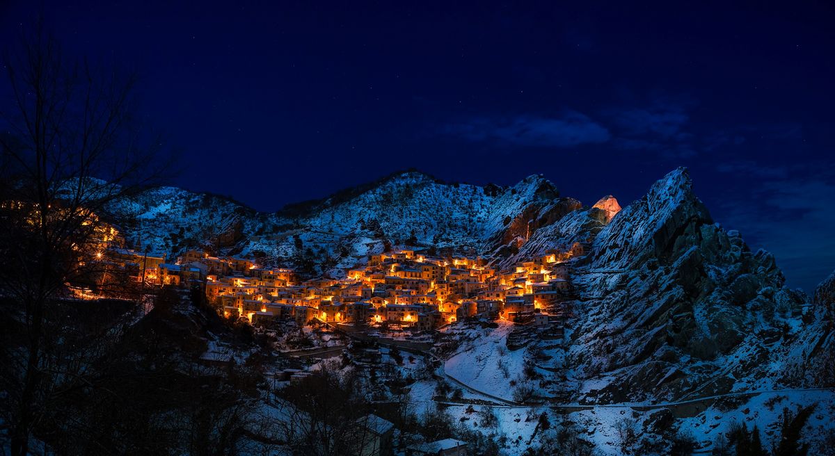 A Christmas village lit at night and covered in snow