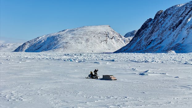 Snowmobile traversing the icy plains with snow-capped mountains in the background, Arctic exploration.