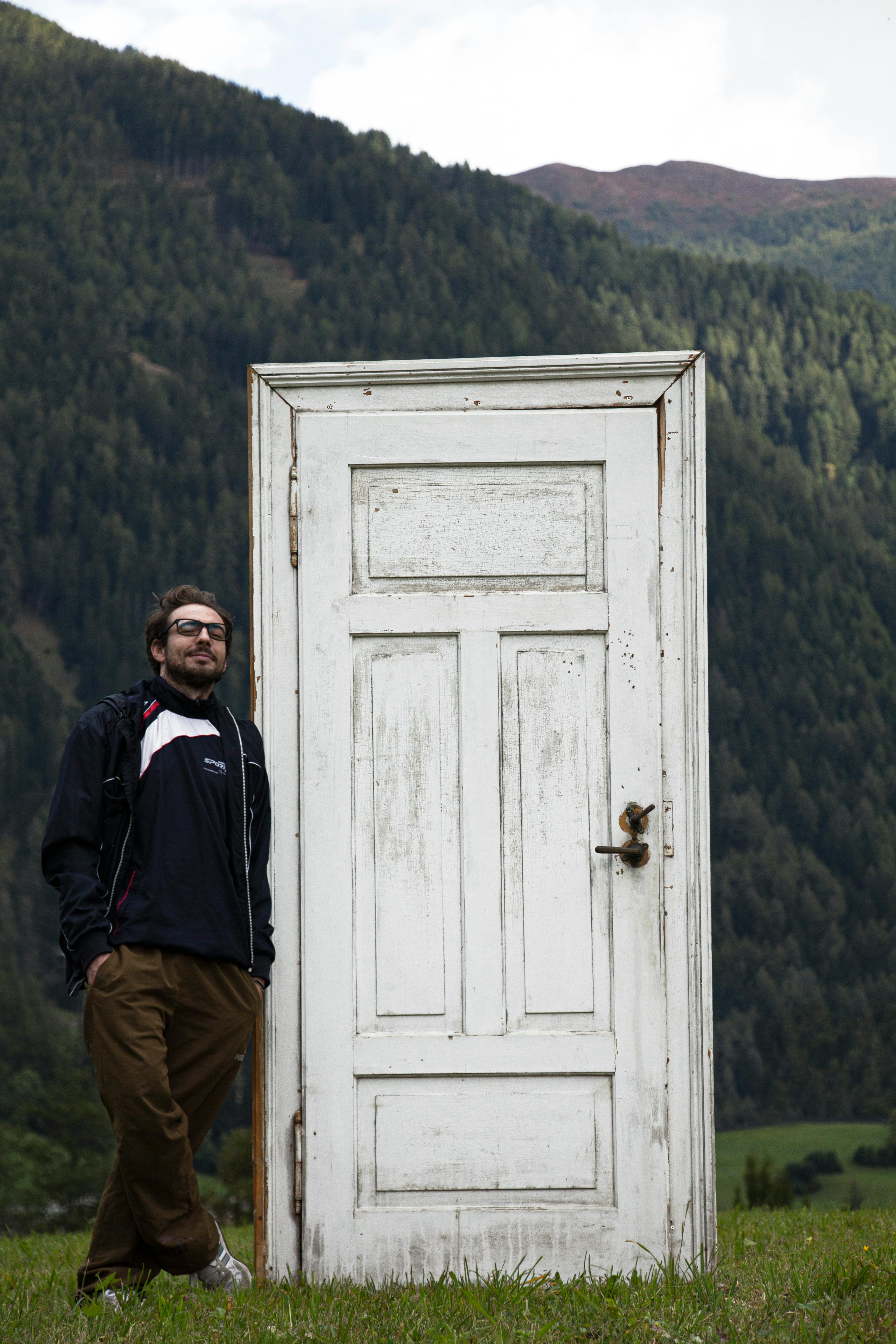 Man standing beside a door in a mountainous meadow in Trentino-South Tyrol, Italy.