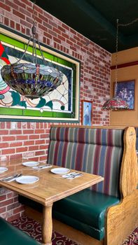 Inviting restaurant booth featuring stained glass window and vintage decor.