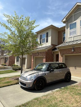 A stylish car parked in front of a suburban home on a sunny day.
