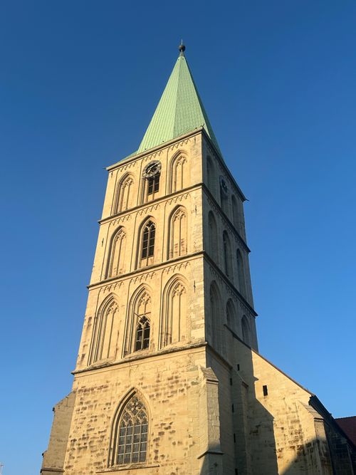 Free Tall Gothic church tower with a green steeple under a clear blue sky, showcasing historic architecture. Stock Photo