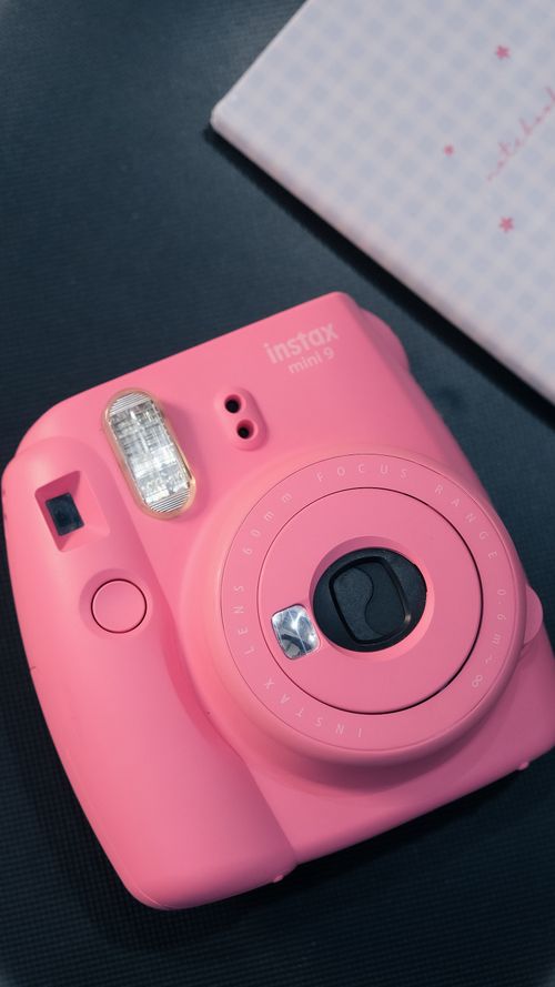 Free Vibrant pink instant camera placed on a dark surface, modern and stylish. Stock Photo