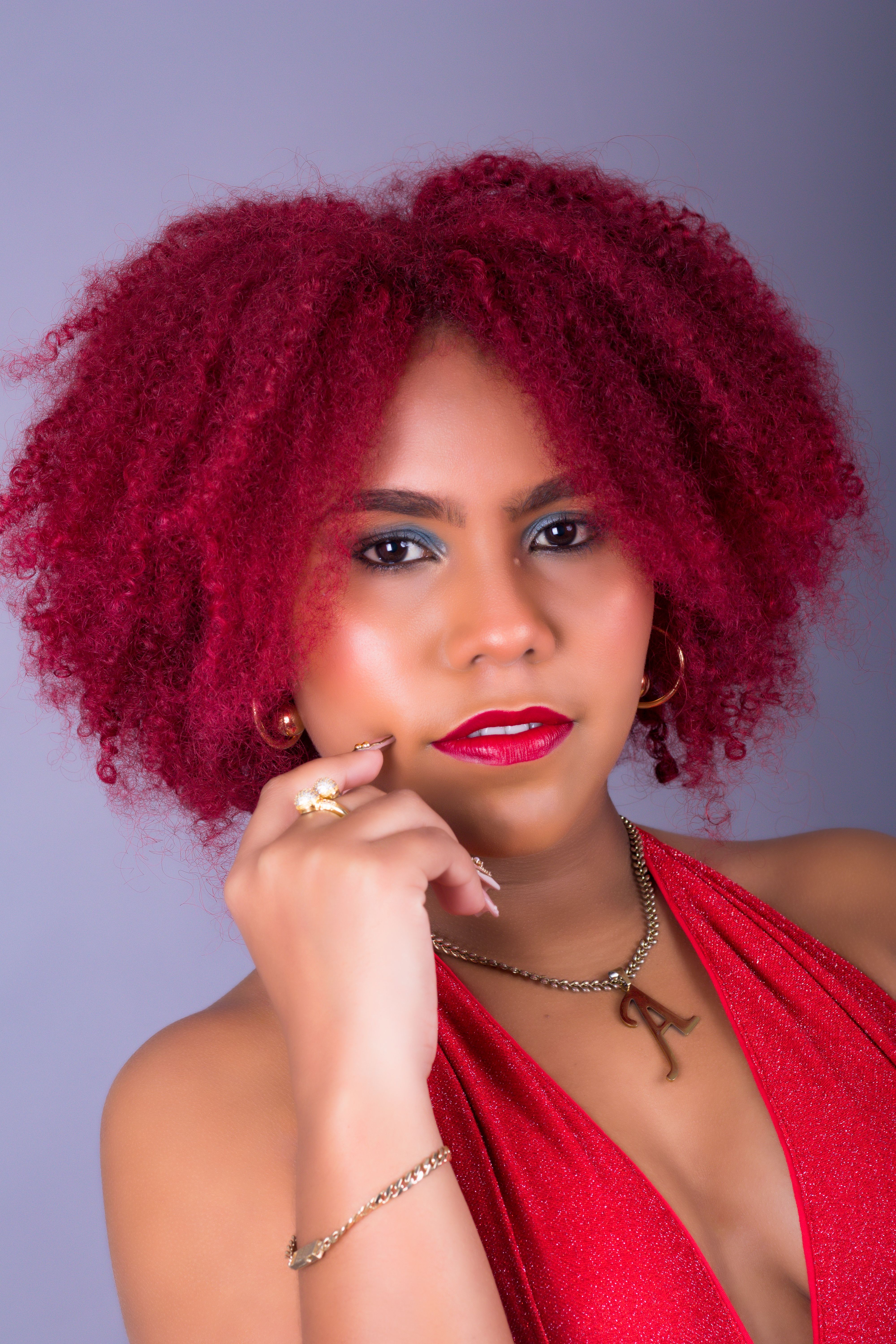Close-up portrait of a woman with vibrant red curly hair and a red dress.