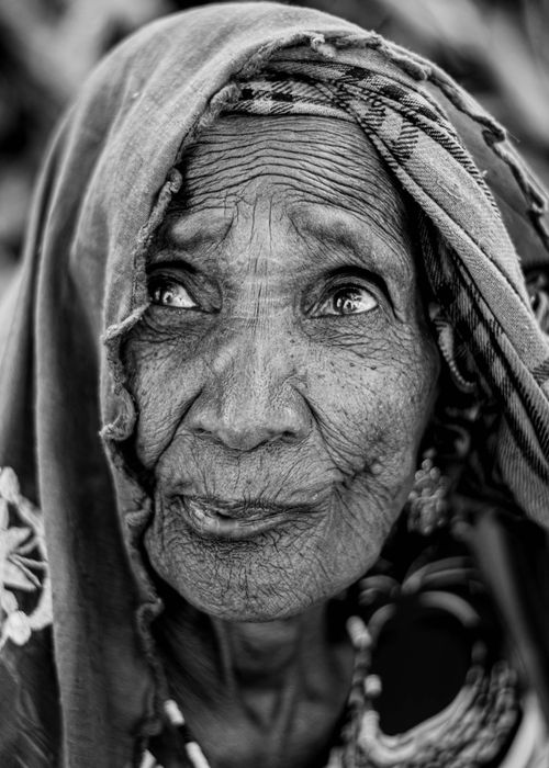 Free Black and white portrait of an elderly woman with expressive eyes wearing traditional attire. Stock Photo