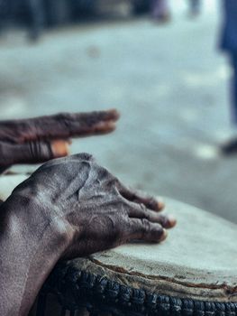 Detailed view of hands rhythmically playing a hand drum, capturing the texture of the skin and instrument.