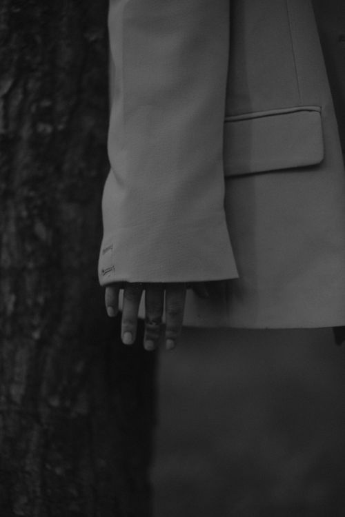 Free Artistic black and white photo of a hand in a jacket sleeve against a tree. Stock Photo