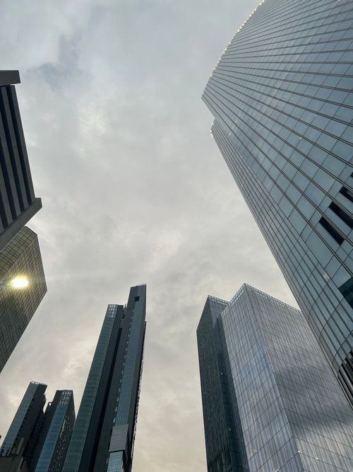 Free Modern skyscrapers ascending towards a cloudy sky, creating a dramatic urban skyline. Stock Photo