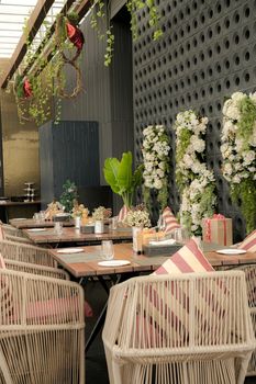 Stylish outdoor dining setup with wicker chairs and elegant floral decor on a sunny day.