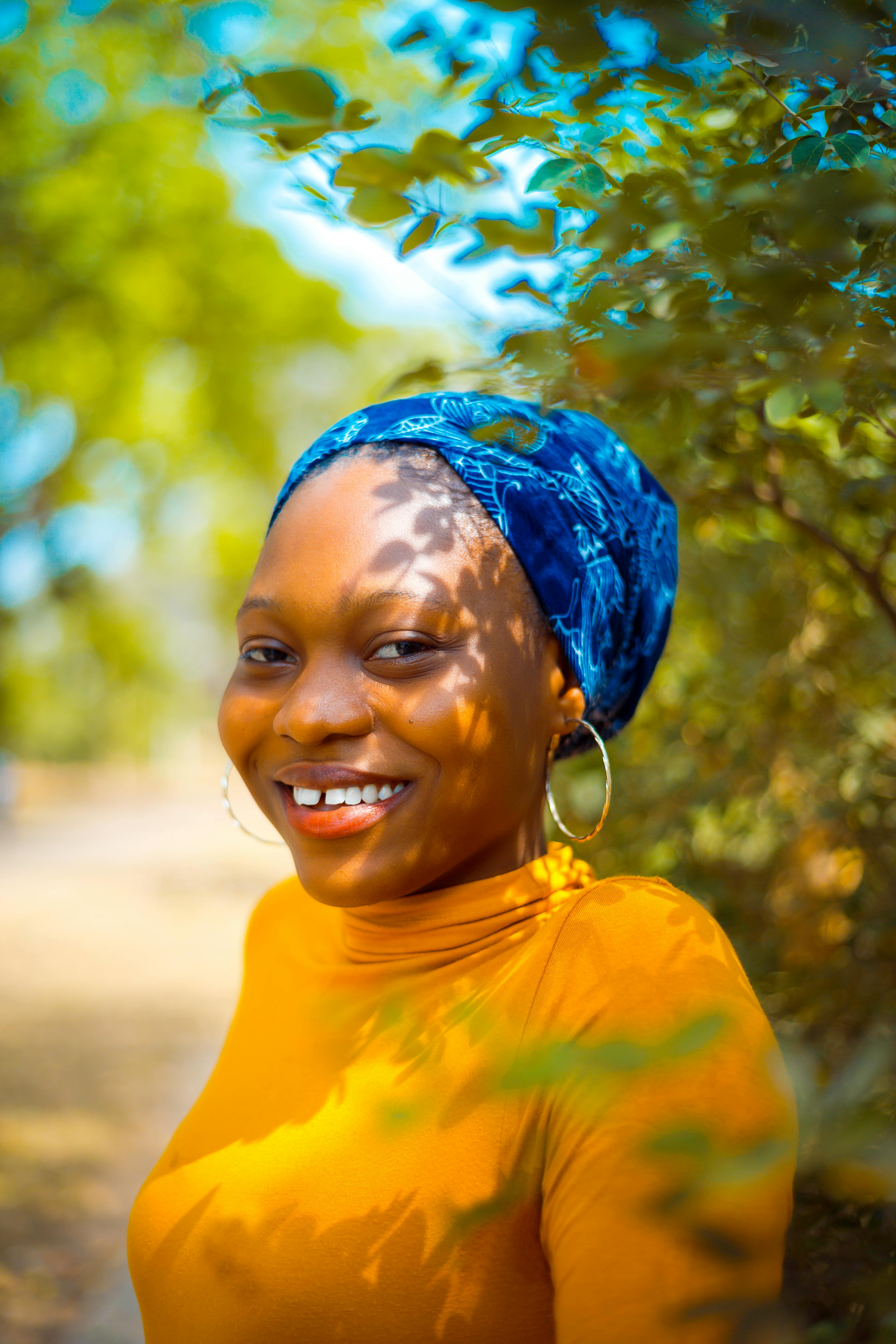 在自然环境中，一位戴着蓝色头巾、面带明亮微笑的女人