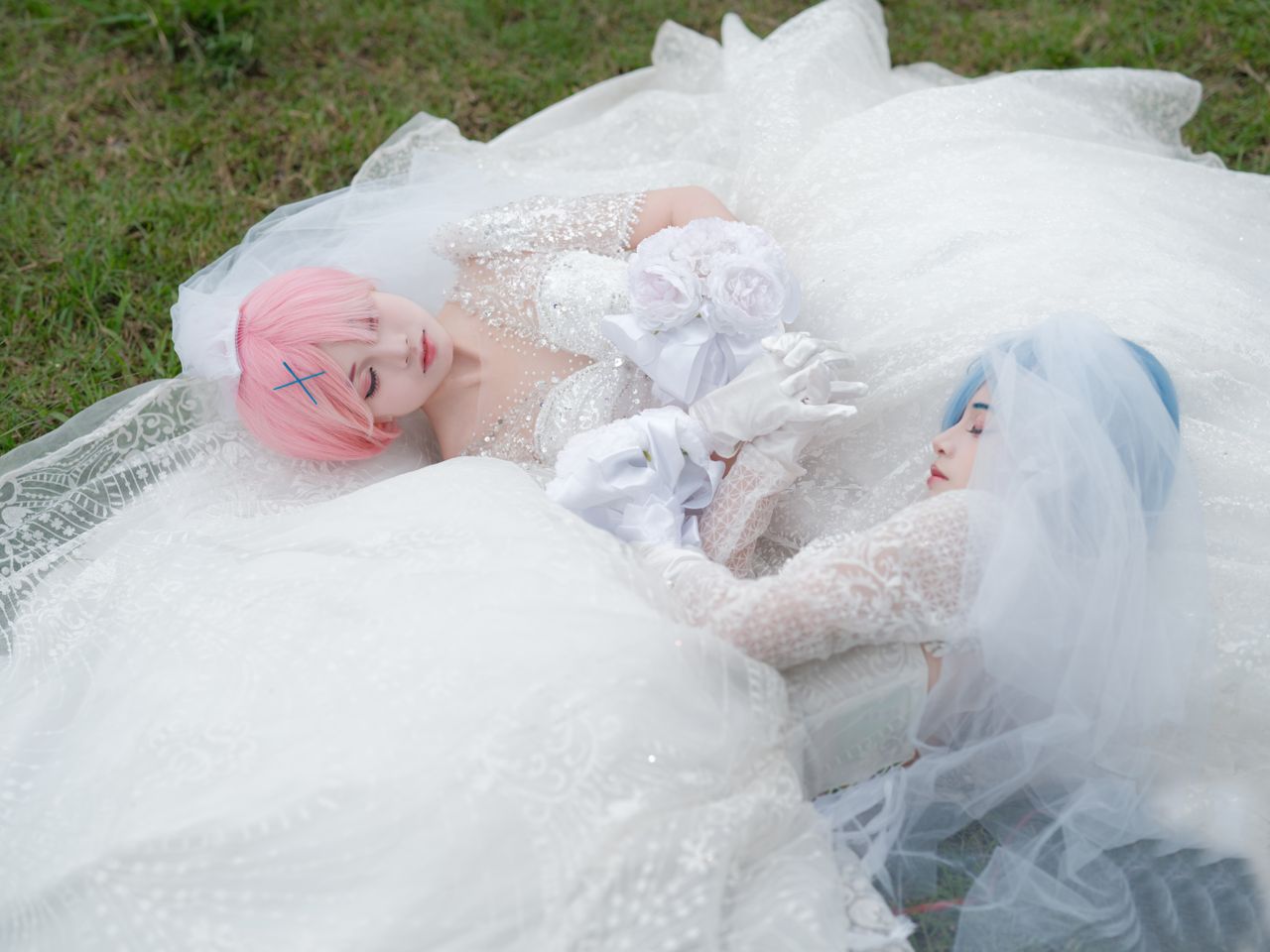 two women in bridal cosplay with pink and blue hair lying outdoors in