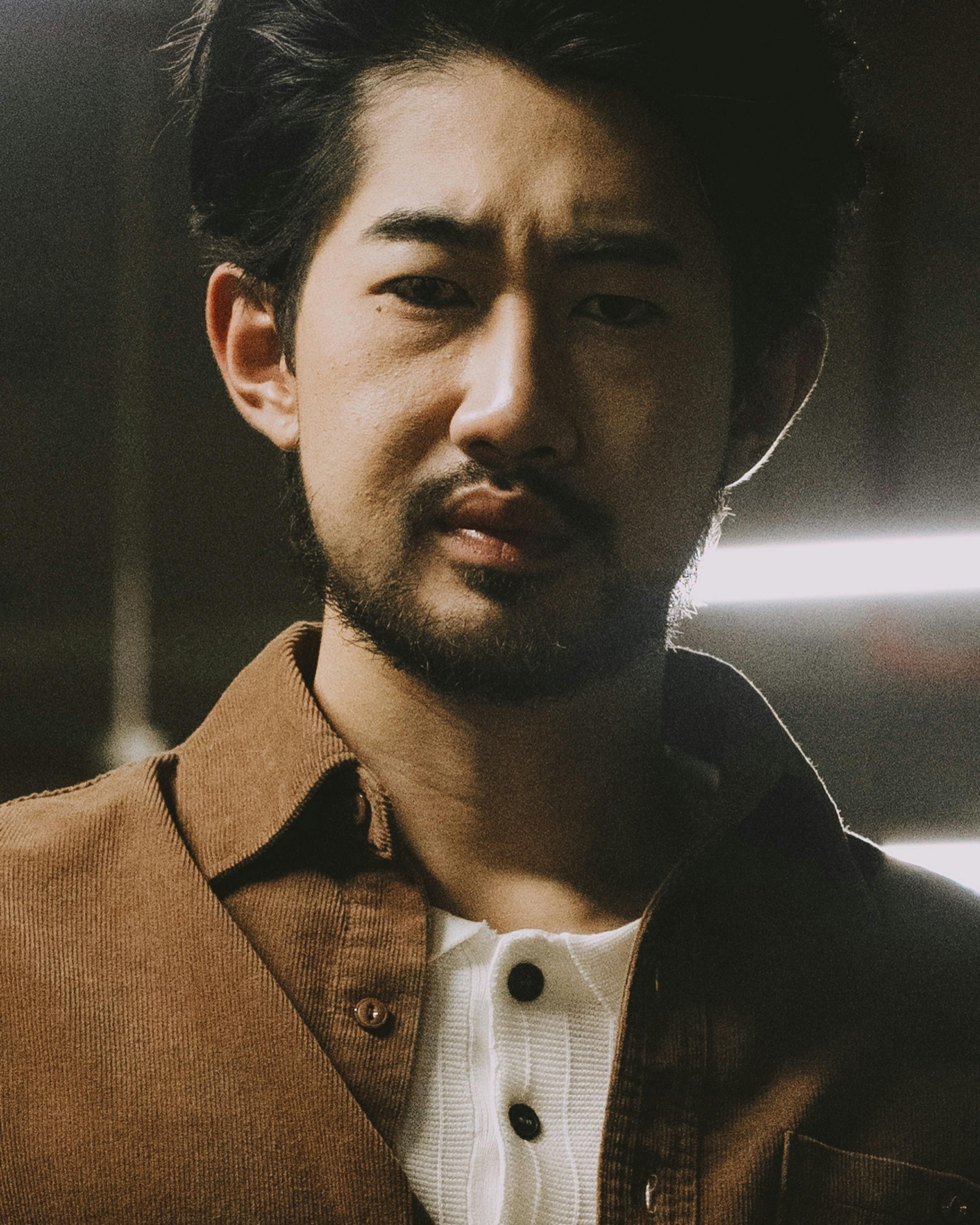 Intense portrait of a man with facial hair in low light, exuding a thoughtful expression.