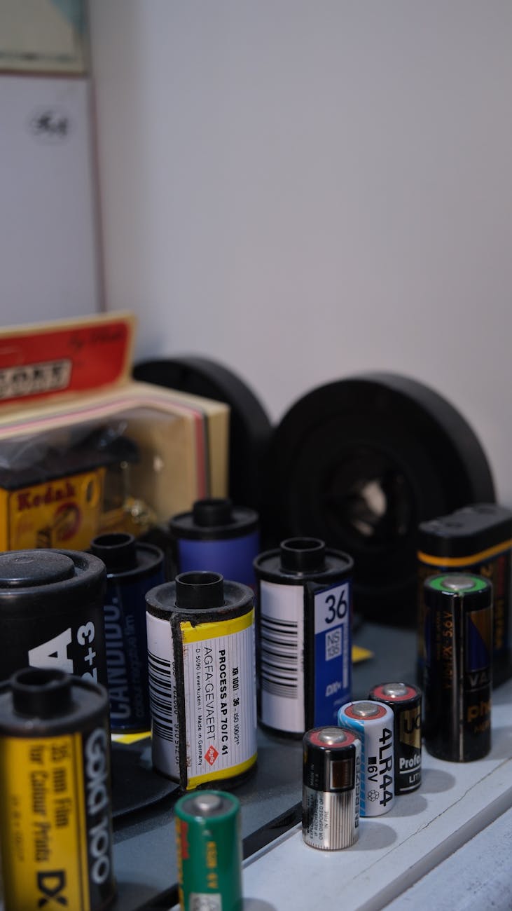 An assorted collection of vintage film rolls and batteries arranged on a shelf.