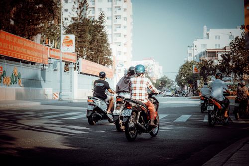 Free Motorcyclists riding in a bustling city intersection on a sunny day. Stock Photo