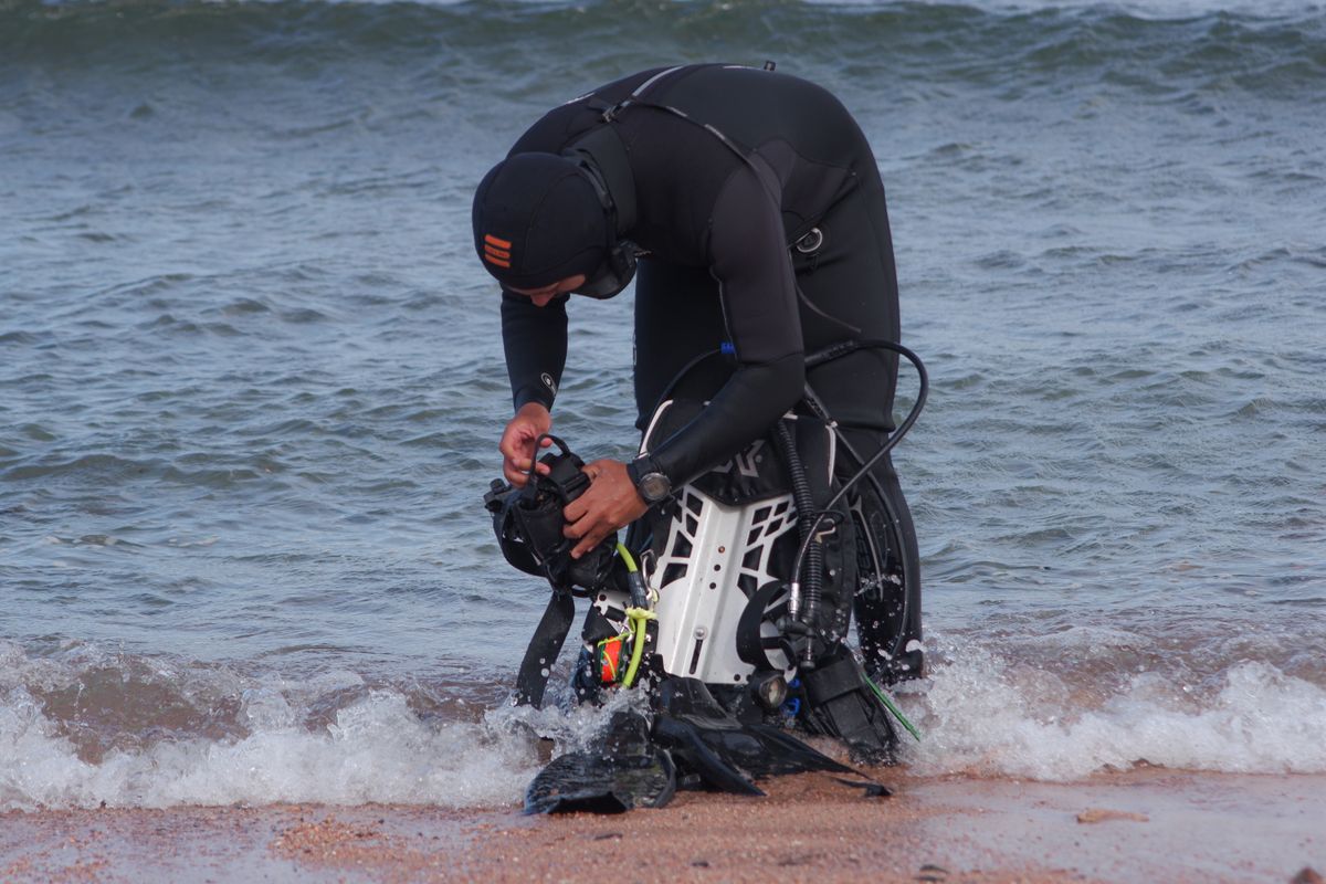 Diver checking equipment at the water's edge